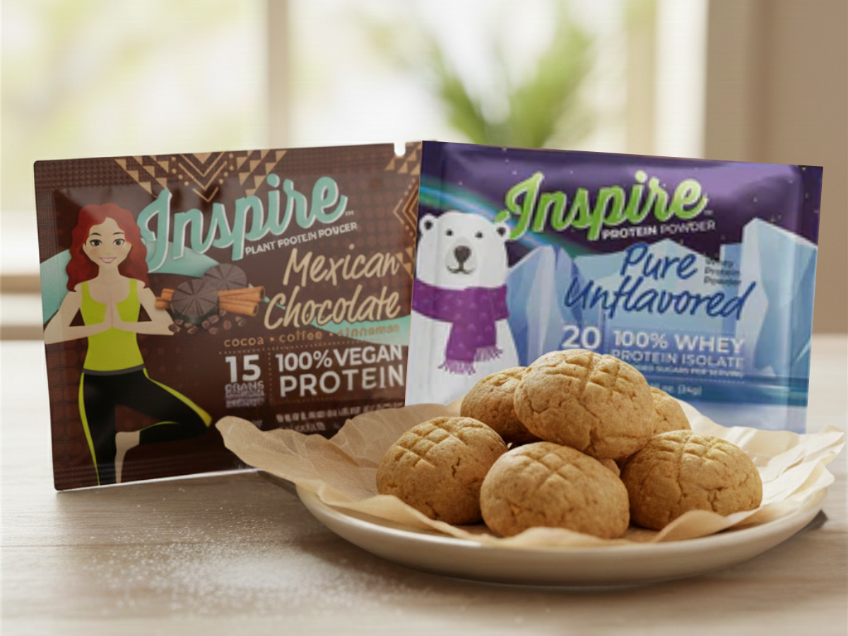 Plate of protein-packed peanut butter cookie bites displayed on a table, with Inspire vanilla and Mexican chocolate protein powder packets placed behind them in a bright, cozy setting.