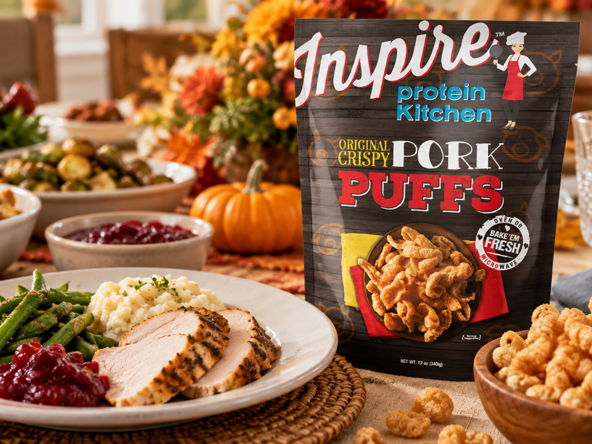 A festive Thanksgiving table displays sliced turkey, green beans, mashed potatoes, and cranberry sauce, alongside a bag of Inspire protein kitchen pork puffs and a small pumpkin for decoration.