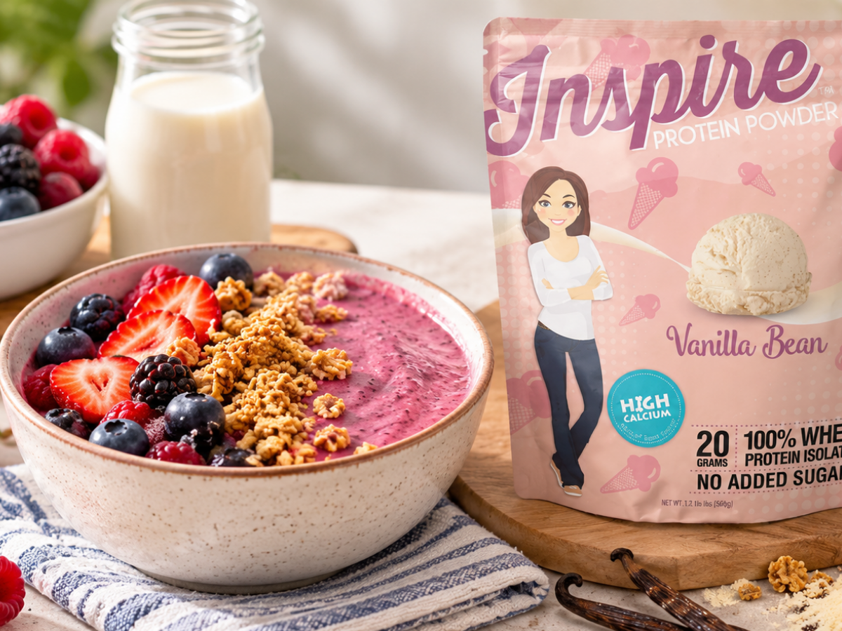 Berry protein smoothie bowl topped with fresh strawberries, blueberries, raspberries, blackberries, and granola beside Inspire Vanilla Bean Protein Powder.