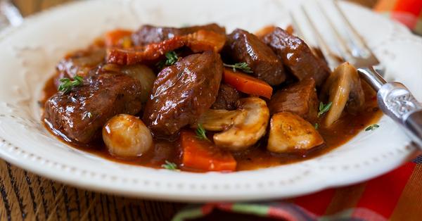 Plate of beef stew with mushrooms, carrots, onions and herbs in a rich brown sauce.