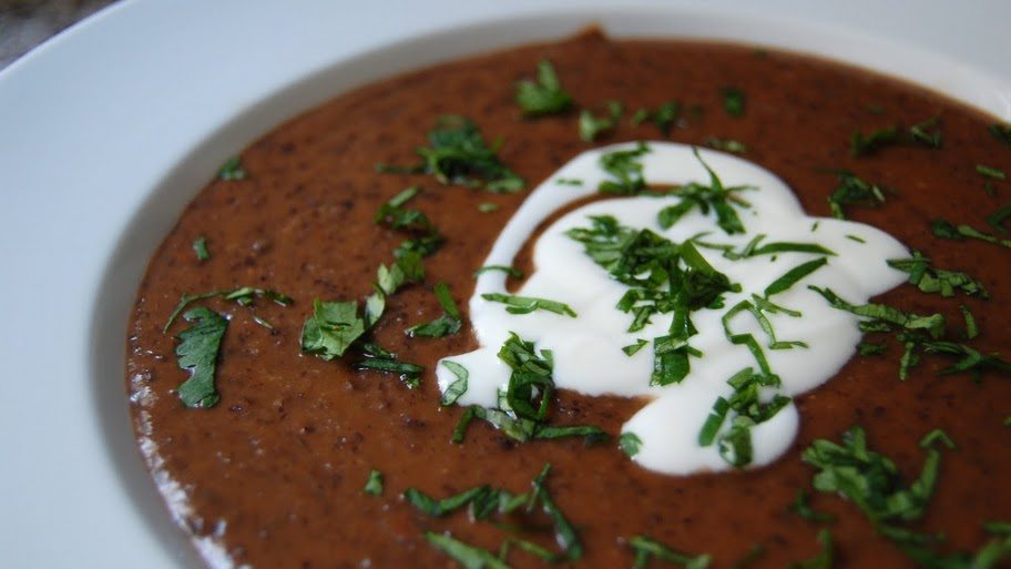 Creamy black bean soup topped with a swirl of sour cream and sprinkled with fresh chopped herbs.