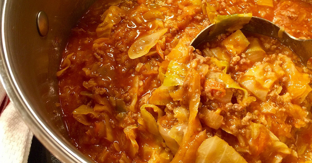Pot of simmering cabbage and ground meat in tomato-based sauce.