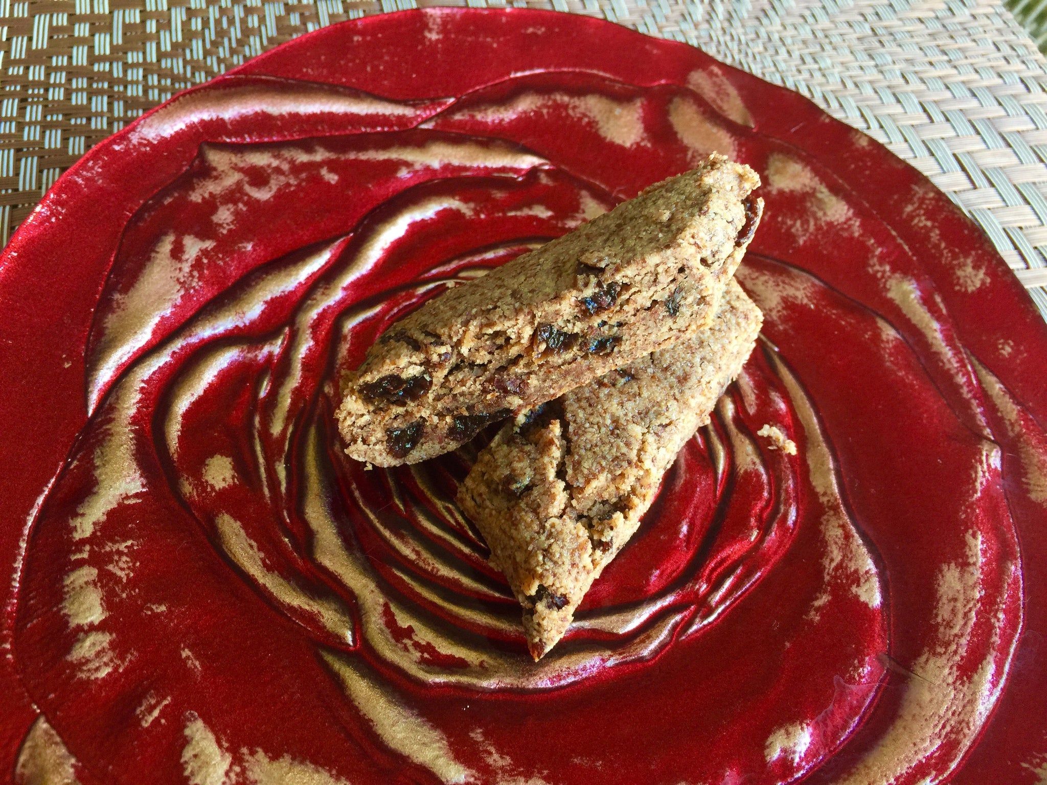 Two homemade oat and raisin bars stacked on a decorative red swirled plate.
