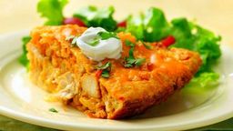 Cheesy chicken casserole slice topped with sour cream and herbs, served with fresh salad.