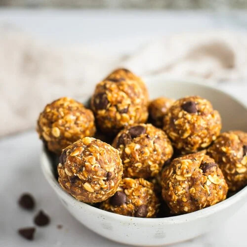 peanut butter balls with chips piled in a ceramic bowl on a kitchen counter