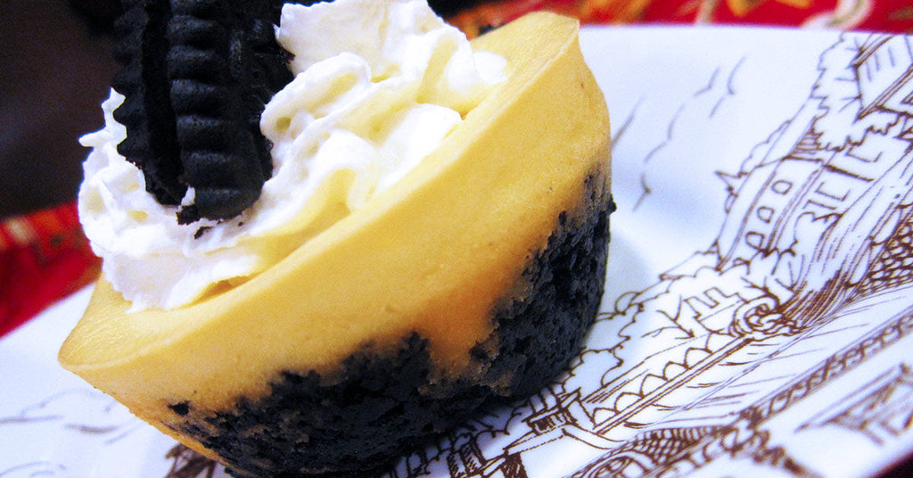 Mini layered dessert with a dark crumb base, creamy top, whipped cream, and a chocolate cookie piece.