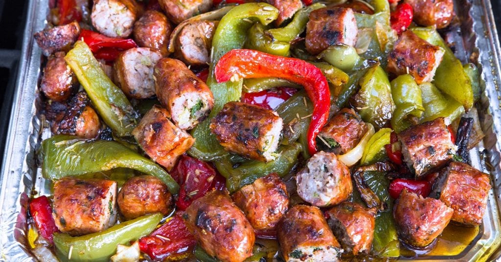 Tray of roasted sausage pieces with sautéed green and red peppers.