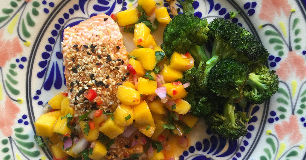 Sesame-crusted salmon with mango salsa and roasted broccoli on a colorful patterned plate.