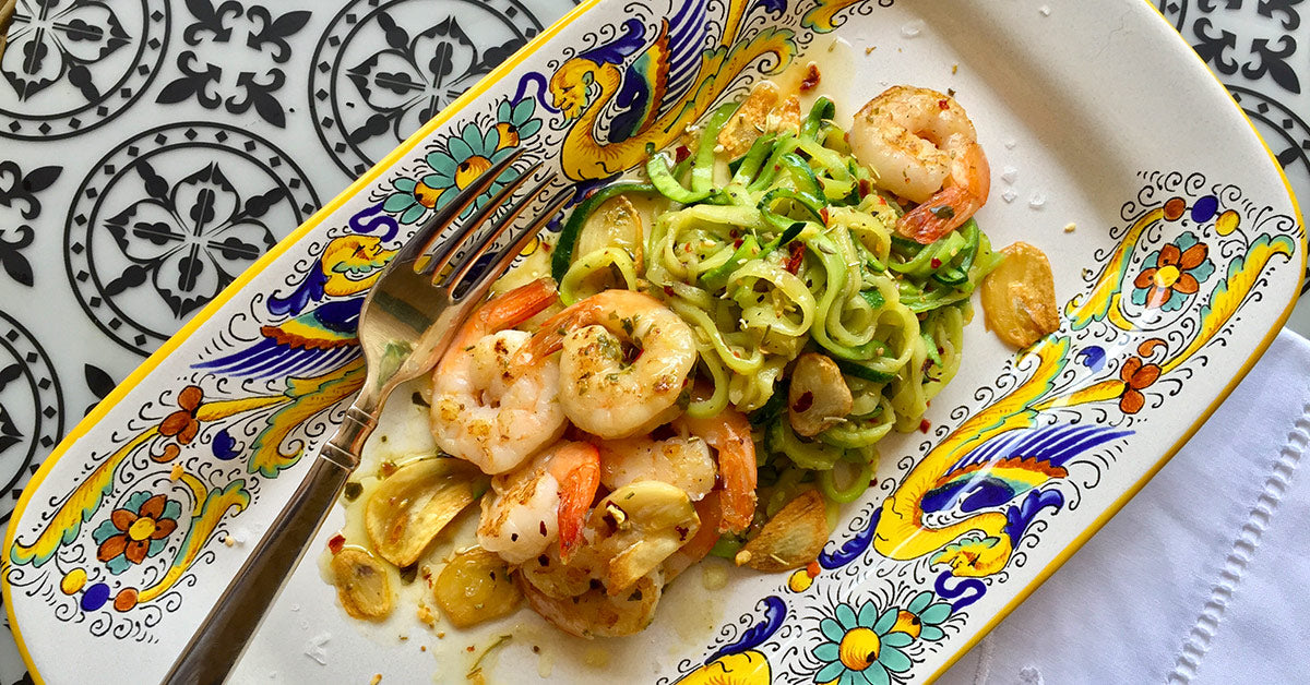 Shrimp and zucchini noodles with garlic on a colorful ceramic plate.