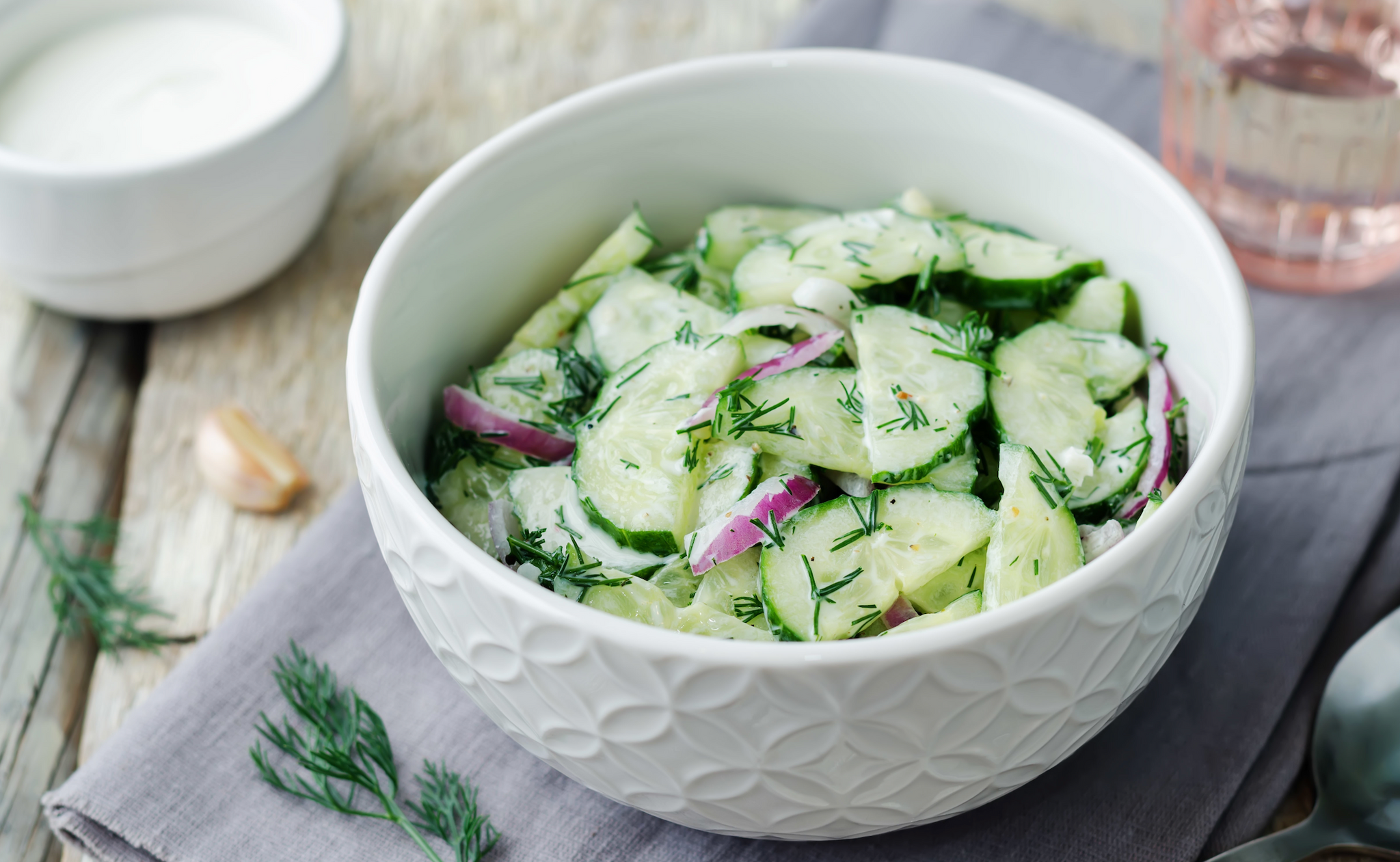 Cucumber and red onion salad with dill in a white bowl.