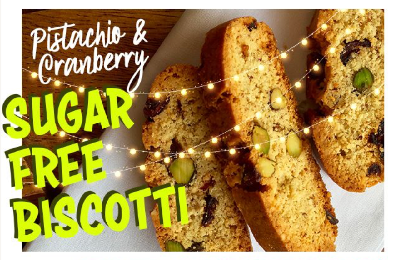 Sugar-free pistachio and cranberry biscotti slices on a cloth, decorated with festive string lights.