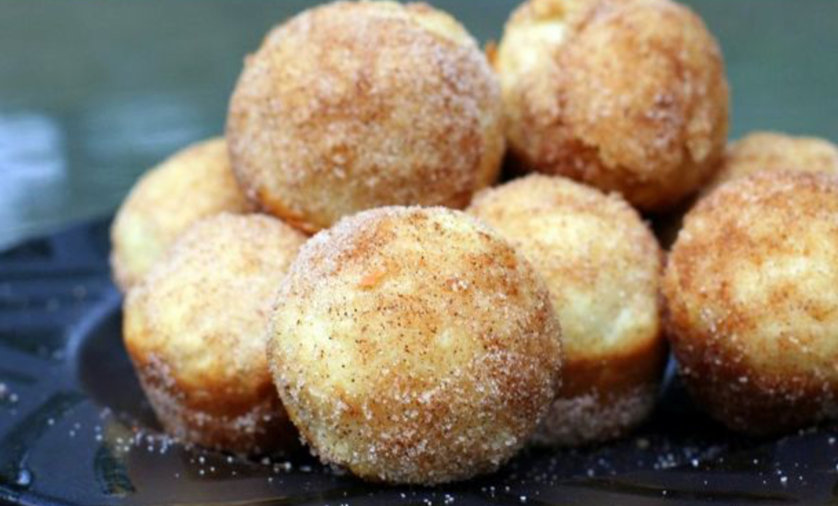 A pile of cinnamon-sugar coated doughnut holes on a dark plate