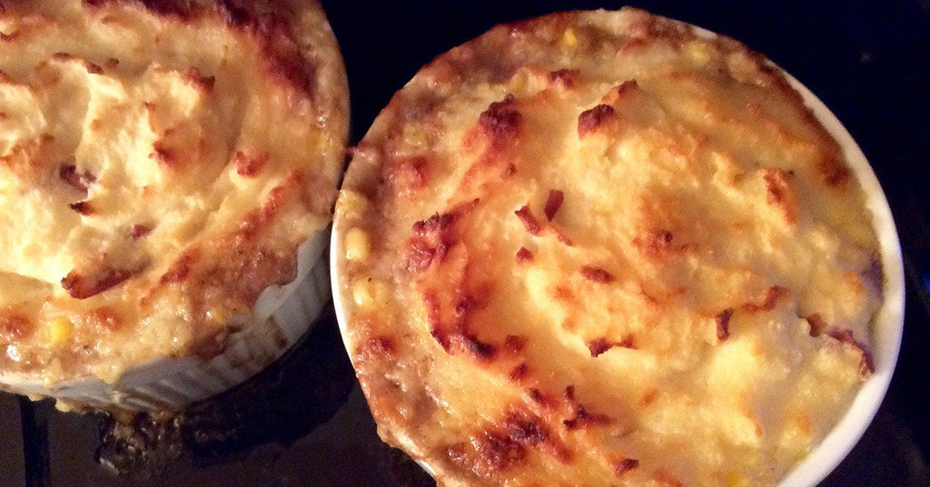 Two small baked casseroles with golden, browned tops in white ramekins.