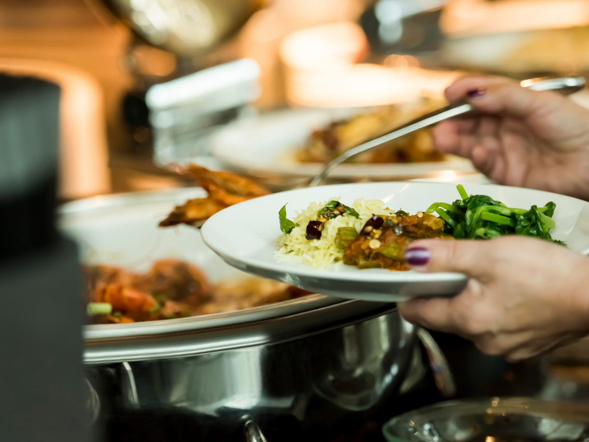 Person standing at a holiday buffet with a small, balanced plate, looking calm and comfortable.