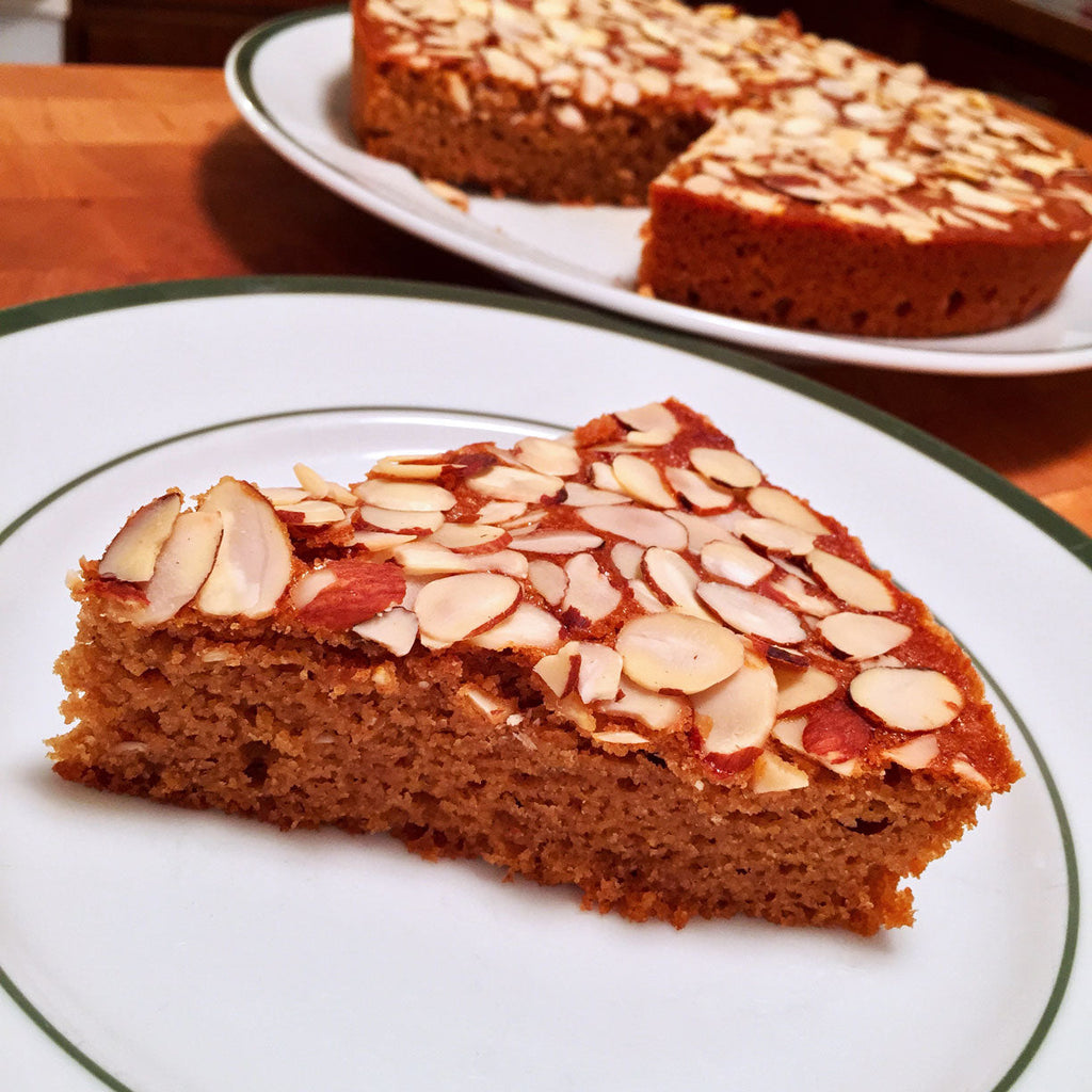 ChatGPT said:  Slice of almond-topped cake on a plate with the rest of the cake in the background