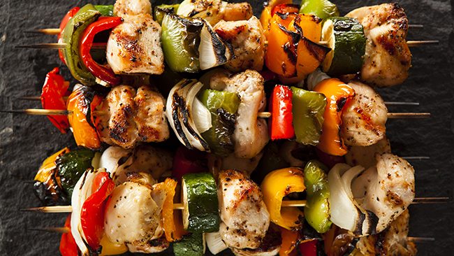 Grilled chicken and vegetable skewers with peppers, onions, and zucchini on wooden sticks.