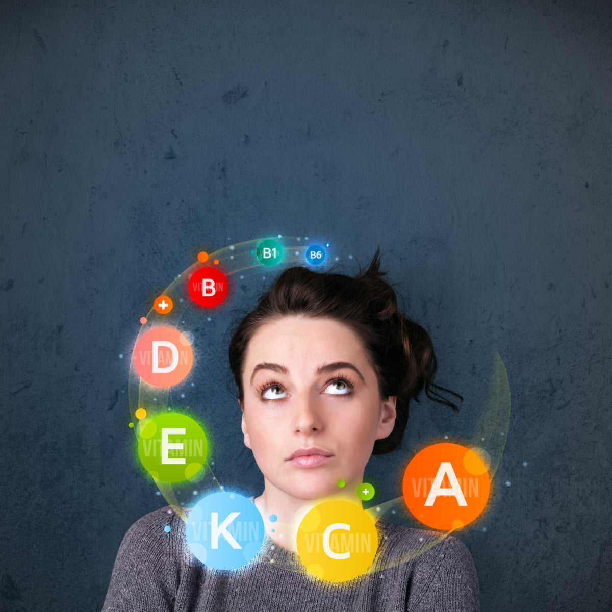 A woman with dark hair looks thoughtfully upward against a textured gray background, surrounded by colorful circles labeled with various vitamins and nutrients.