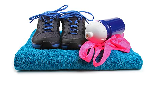 Running shoes, a water bottle, and a pink headband placed on a folded blue towel.