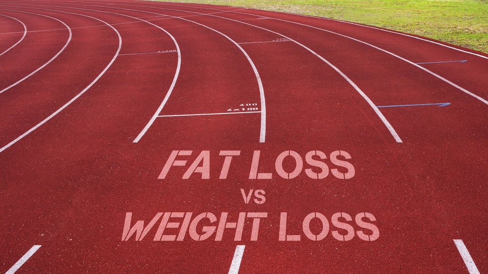 A red running track features the words "FAT LOSS vs WEIGHT LOSS" painted on it, highlighting the comparison between two fitness concepts.