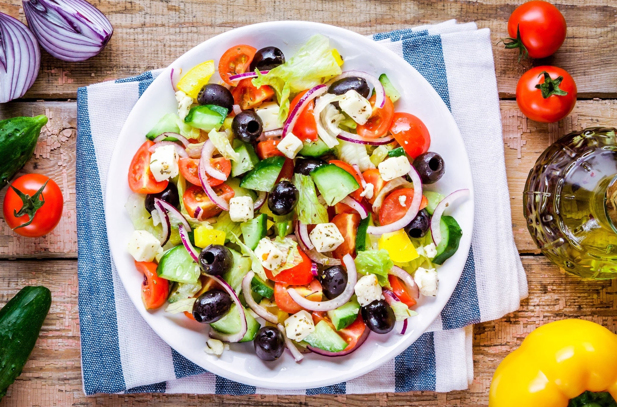 Colorful Greek salad with tomatoes, cucumbers, olives, red onions, and feta in a white bowl.