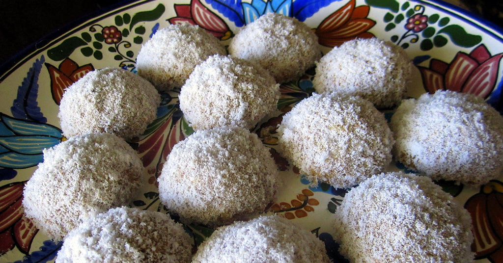 Powdered sugar–coated cookie balls arranged on a colorful floral plate.