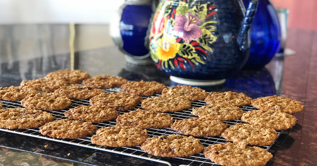 Cooling rack filled with oatmeal cookies on a kitchen counter with colorful pottery in the background.