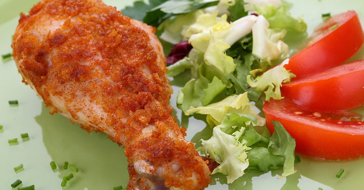 Crispy baked chicken drumstick served with fresh mixed greens and sliced tomatoes.