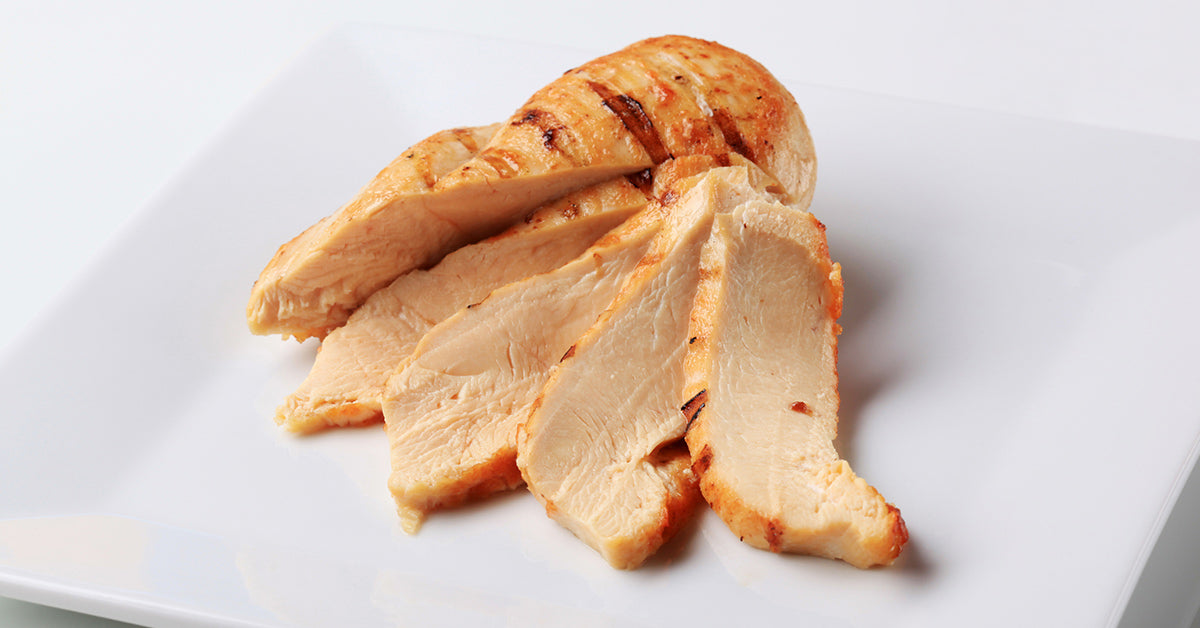 Slices of cooked, golden-brown chicken breast arranged on a white plate.