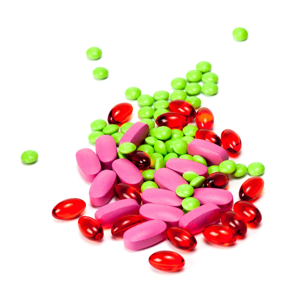 Colorful assortment of pills and capsules, including pink tablets, red gel capsules, and small green round pills.