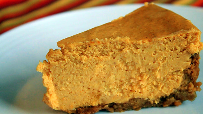 Slice of creamy pumpkin cheesecake with a spiced crust on a white plate.