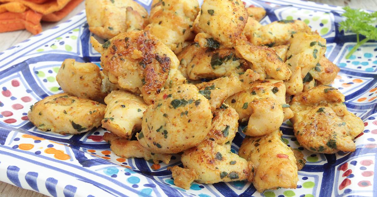 Plate of seasoned, sautéed chicken pieces with herbs served on a colorful patterned dish.
