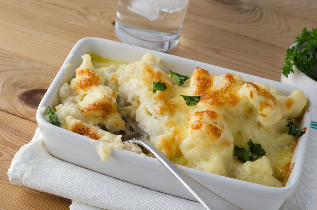 mashed cauliflower in a white bowl with parsley garnish, creamy protein-packed mashed cauliflower for Thanksgiving