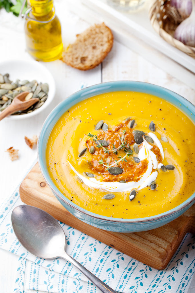 Bowl of creamy high-protein butternut squash soup topped with Greek yogurt and pumpkin seeds