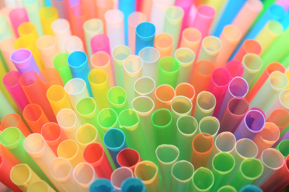 A close-up view of colorful drinking straws in various shades of pink, blue, green, yellow, and orange, arranged closely together, creating a vibrant and cheerful pattern.